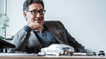 Porträt eines Mannes im Büro, sitzend an einem Schreibtisch mit Automodell.